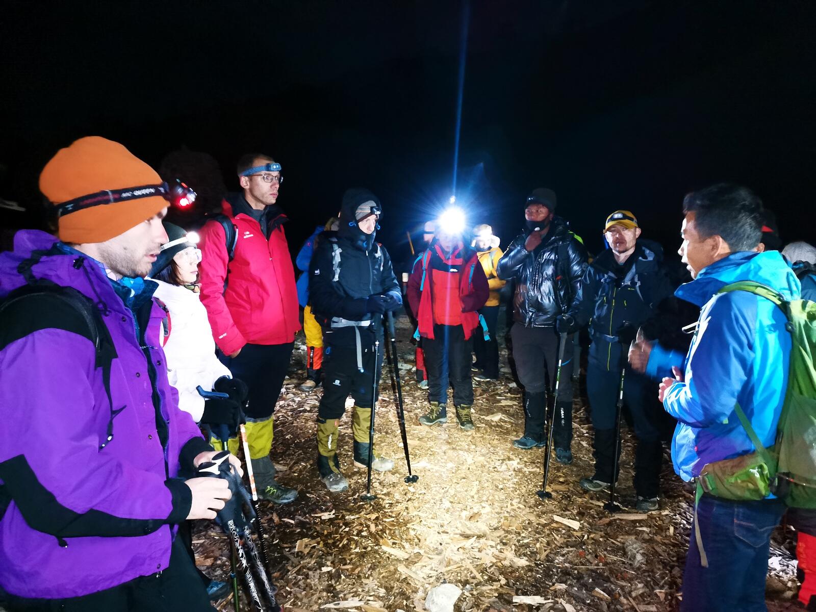 Pre-dawn safety briefing at the trailhead, headlamps lit.
