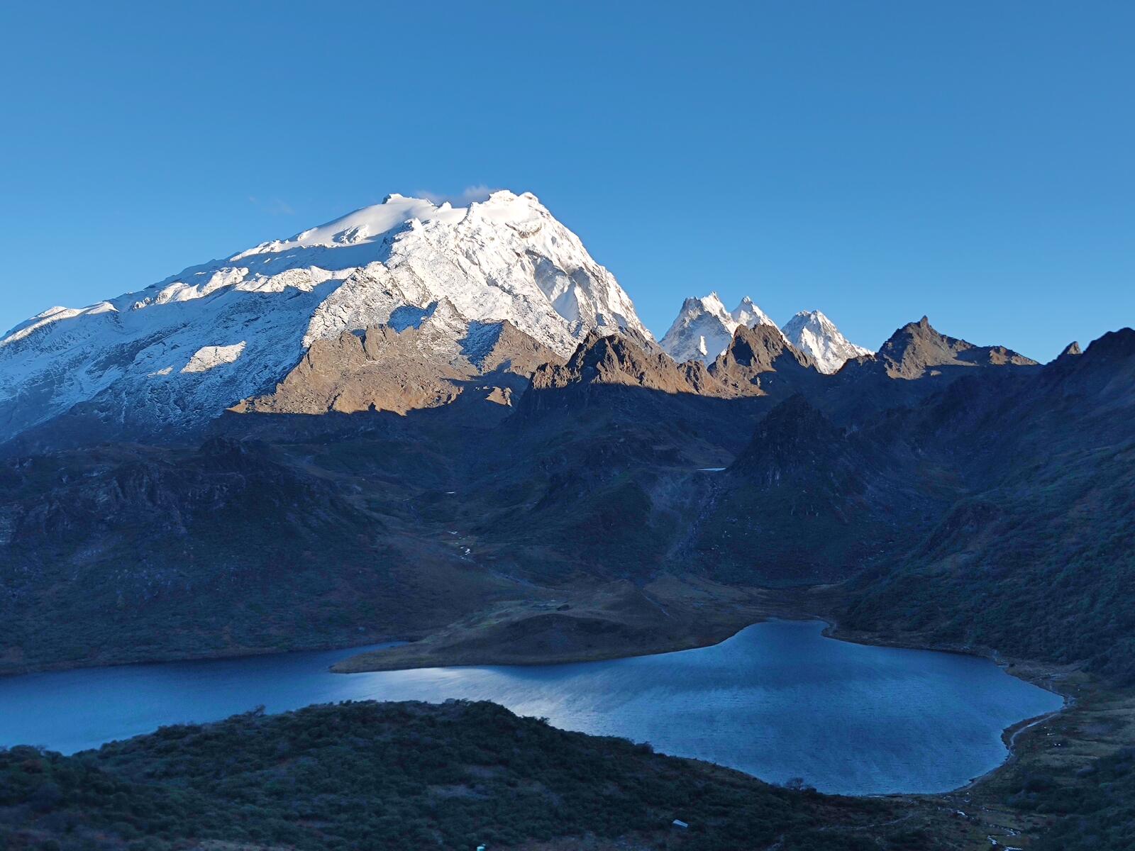 Turquoise glacial lake beneath the Haba massif, with camp visible on the peninsula.
